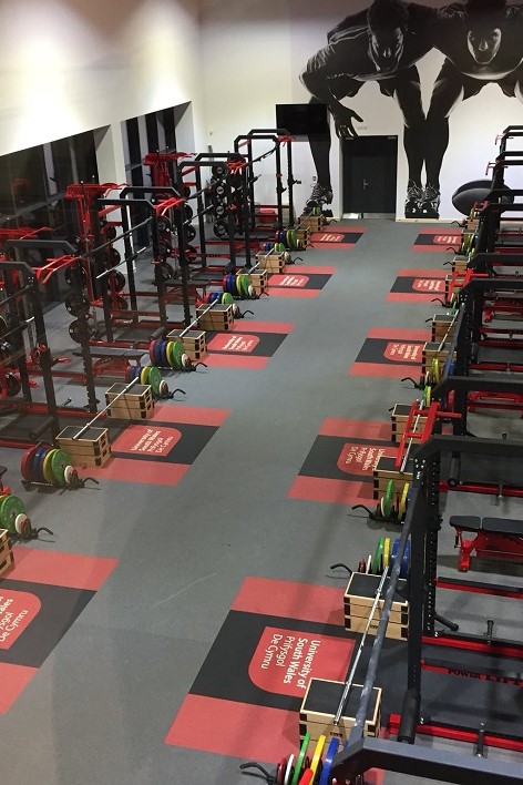 Multiple Power Racks with weights and barbells, from above