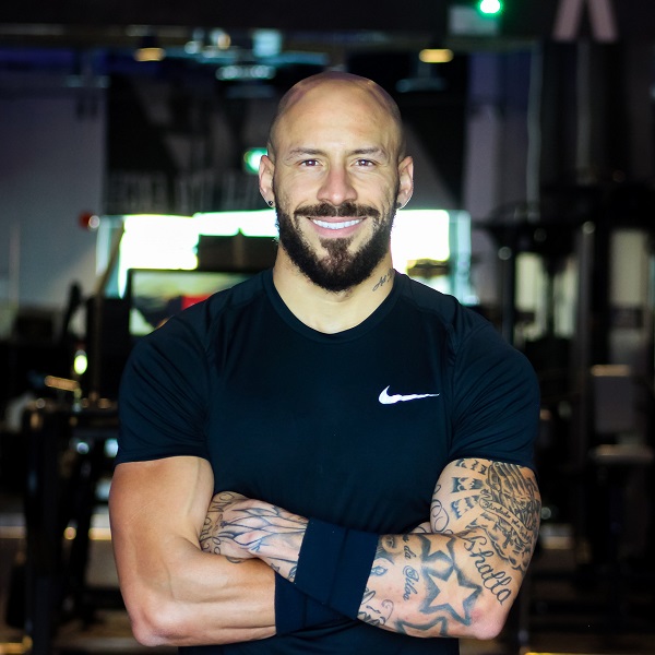 Muscular white bald man with beard, tatoos and crossed arms smiling