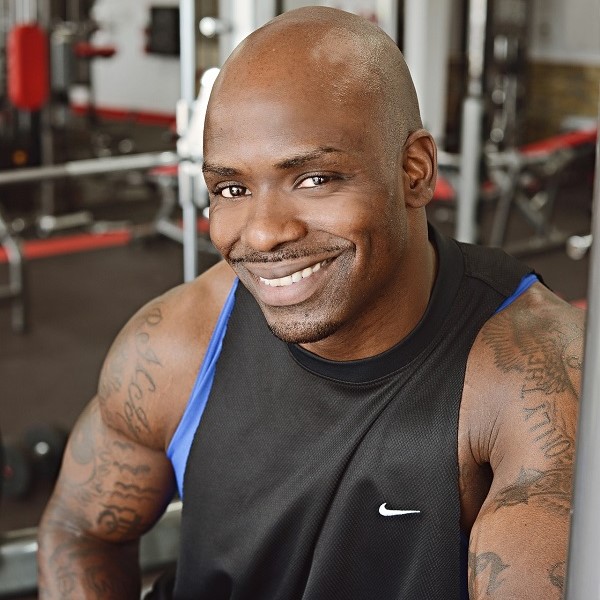 Muscular bald black man smiling wearing a tank top